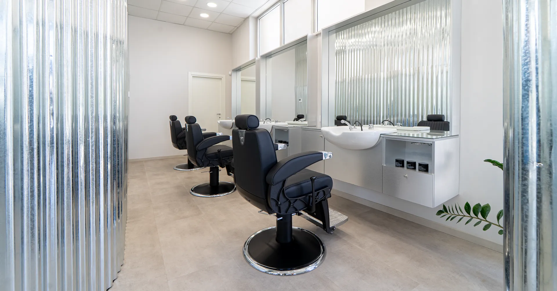Postazioni di lavoro del salone Gianluca Spagnolo Hairlab con poltrone nere e specchi