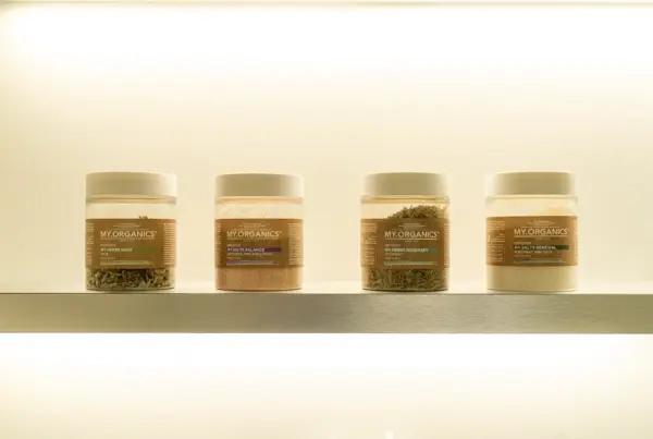 Quattro barattoli My.Organics con erbe e sali su una mensola illuminata della cabina Hair Spa